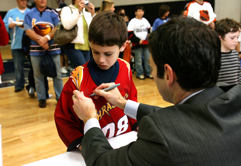 Thrashers player Mathieu Schneider signs a jersey during the player meet and greet.